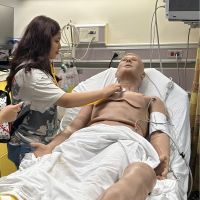 student checks heartbeat of training mannequin 