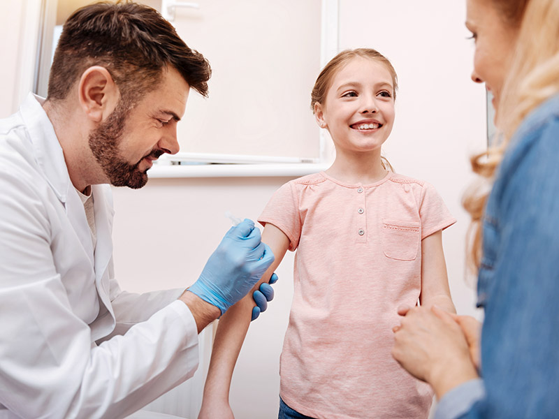 Male doctor gives vaccine to young girl