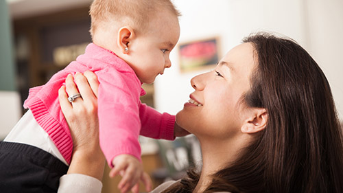 A smiling mom holds up a baby