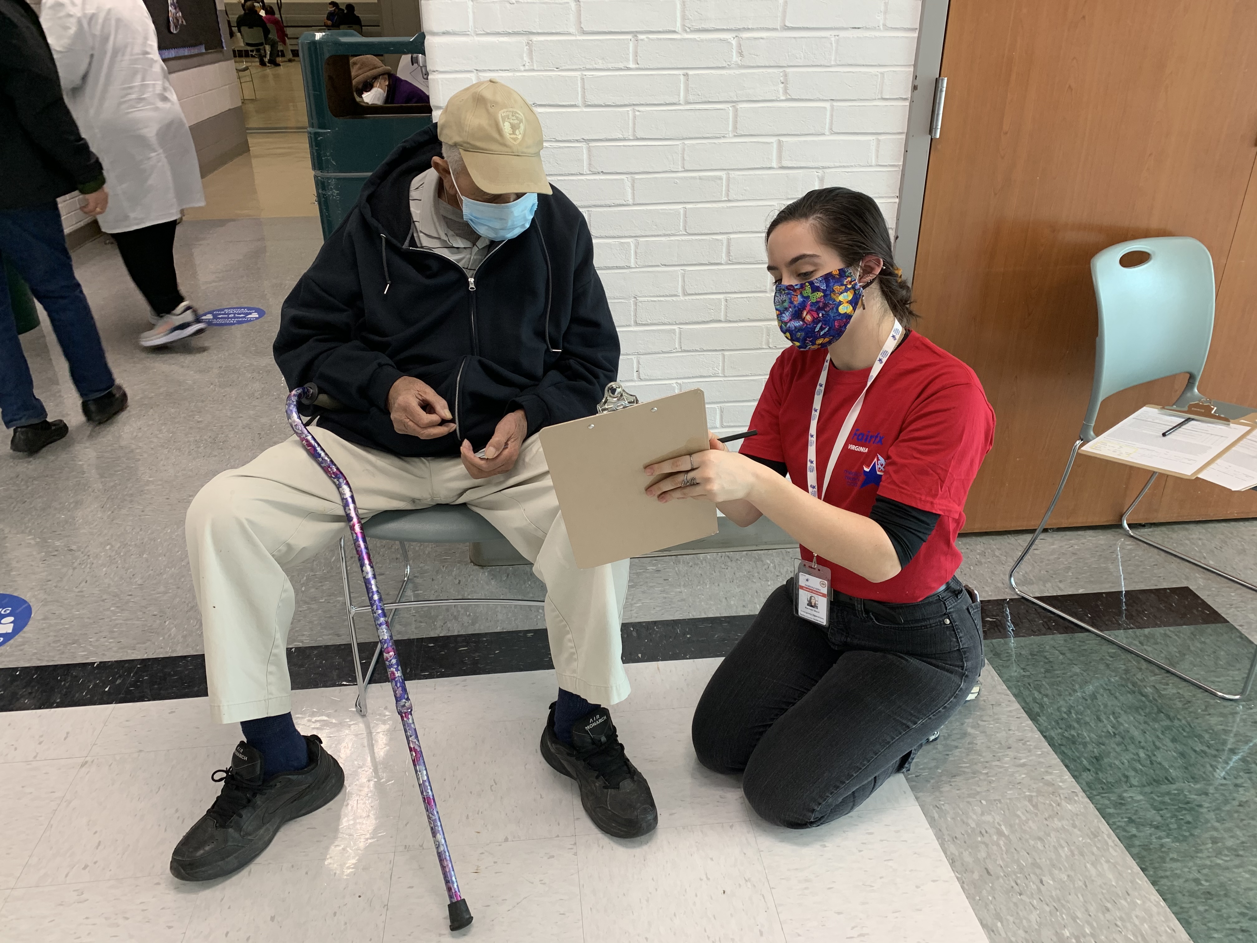 MRC volunteer assisting a man at a vaccine clinic