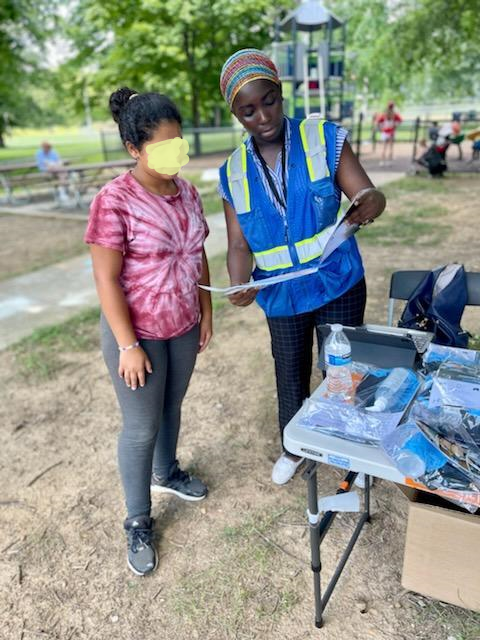 Community health worker showing someone flyers at a farmers market