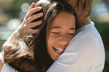 Photo of teen girl smiling and hugging mother