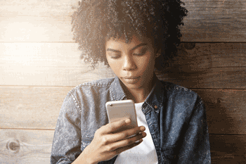 Photo of young African American woman looking at cell phone