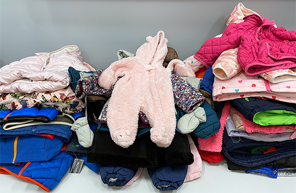Children's coats in a pile on a table.