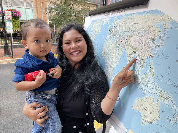 Woman with child pointing a world map at the Reston Multicultural Festival