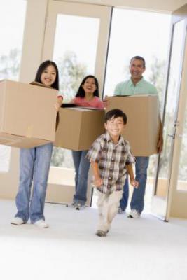 family holding boxes walking in front door