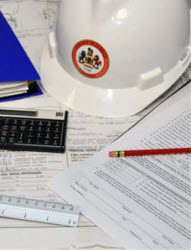 construction hat, papers, calculator, pencil and binder on desk