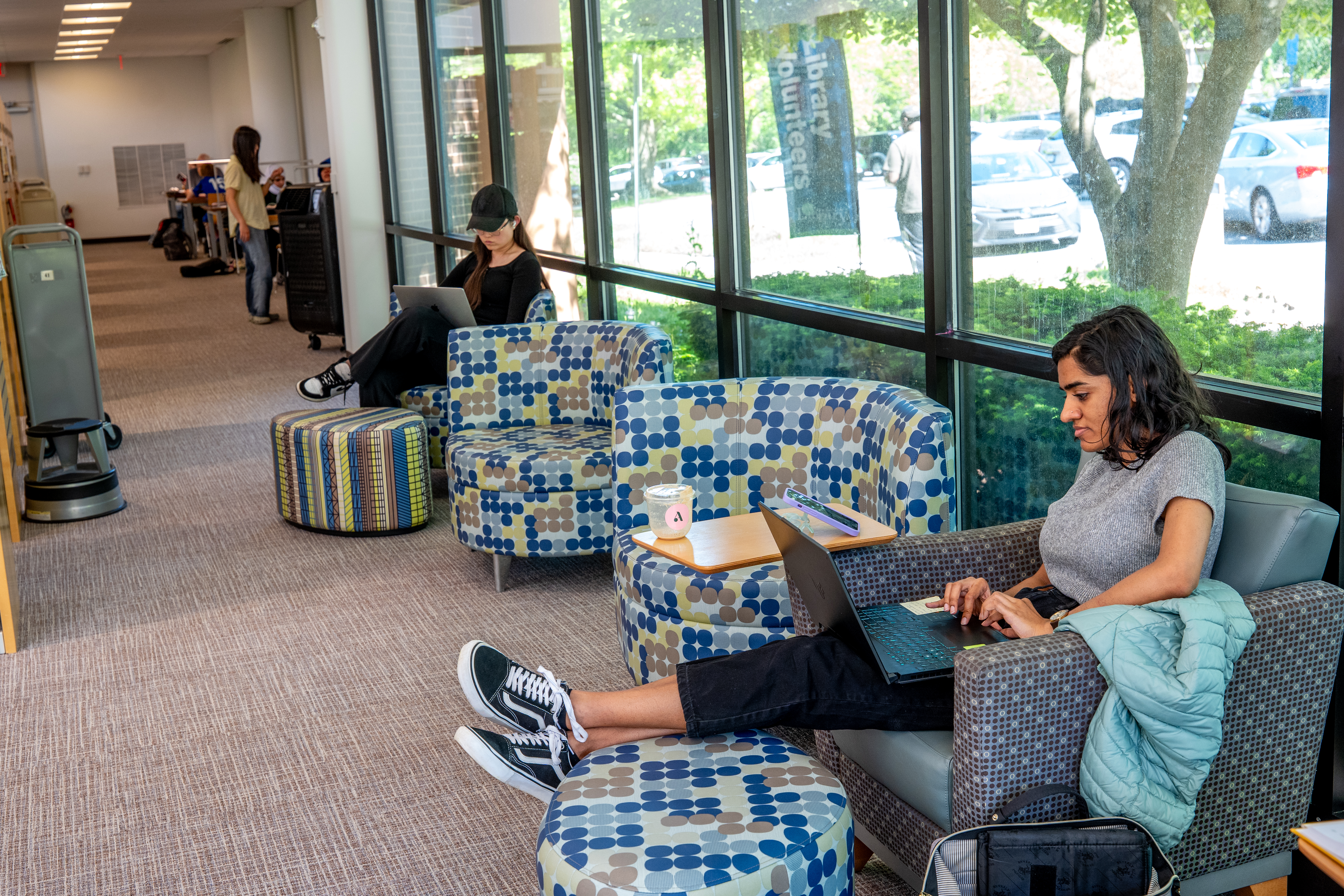 two young women sitting in chairs and working on laptops