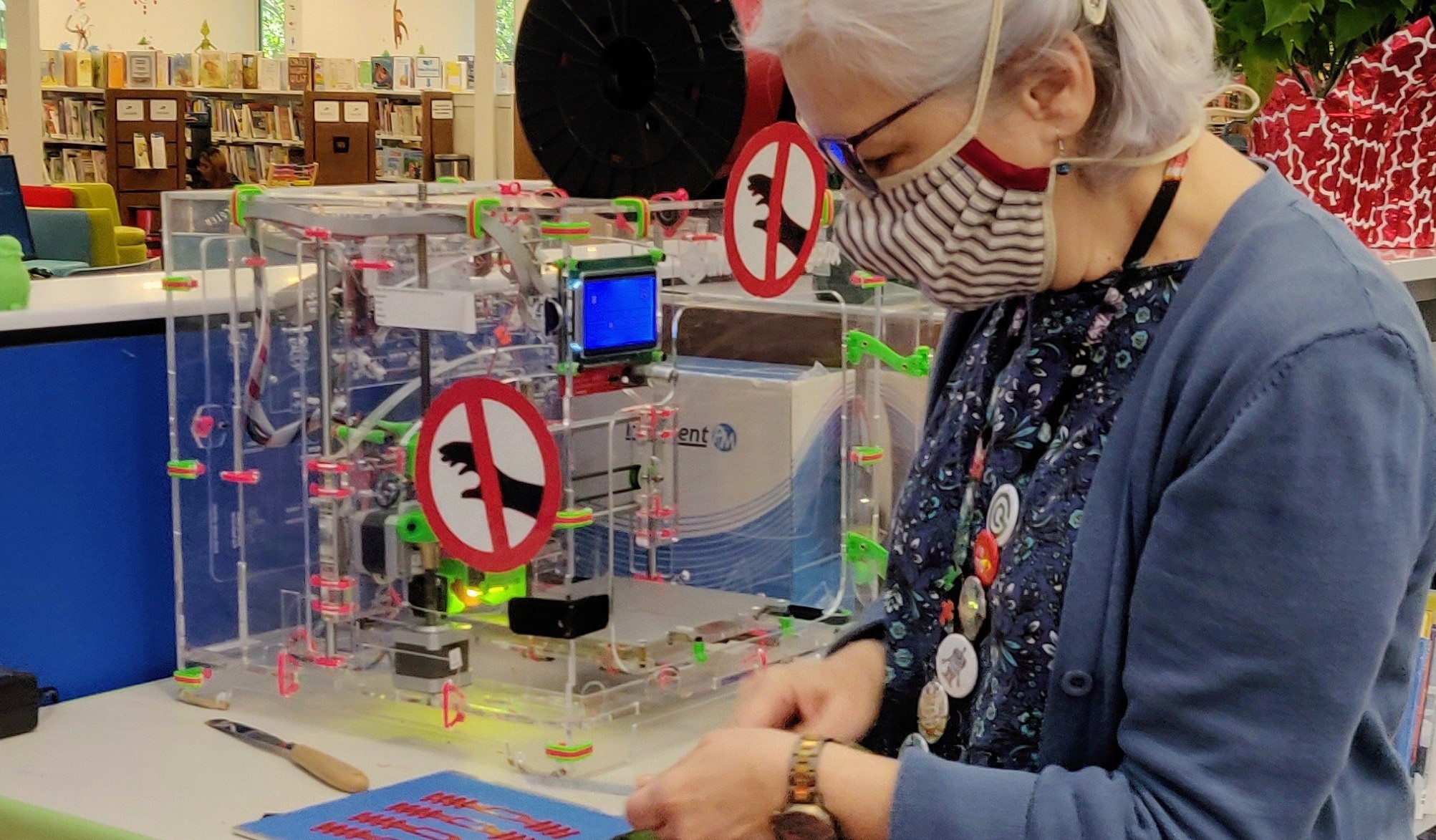 woman in a face mask cuts out 3D printed mask comfort bands in front of a 3D printer