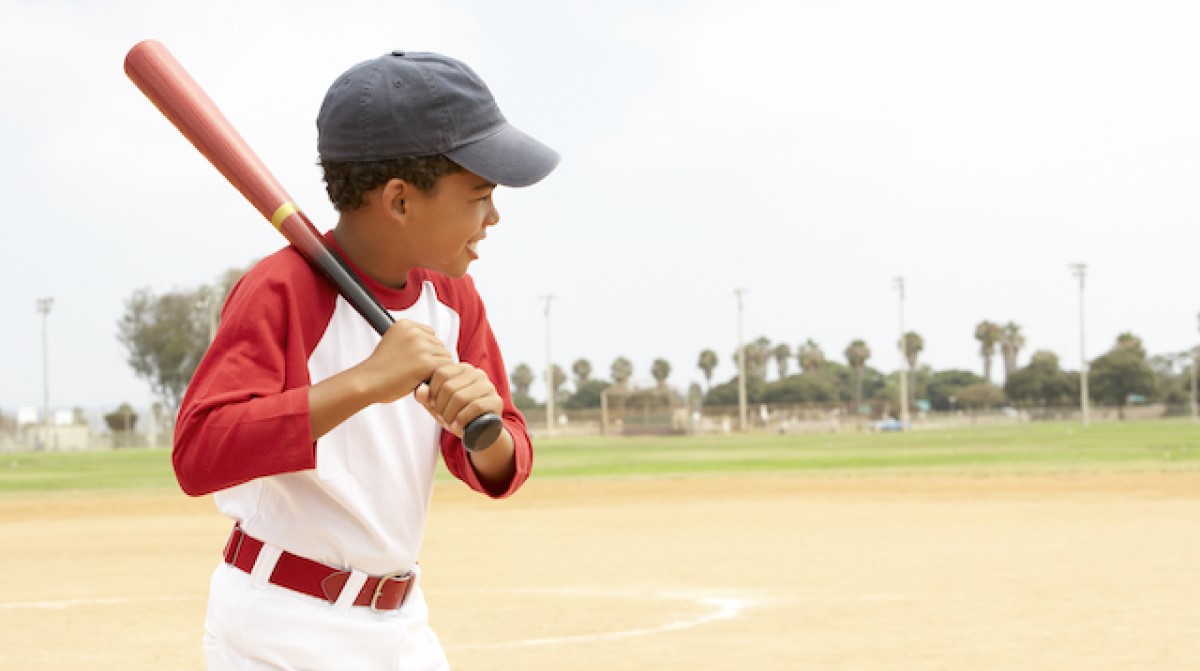 boy dressed in a baseball uniform holding a bat to swing