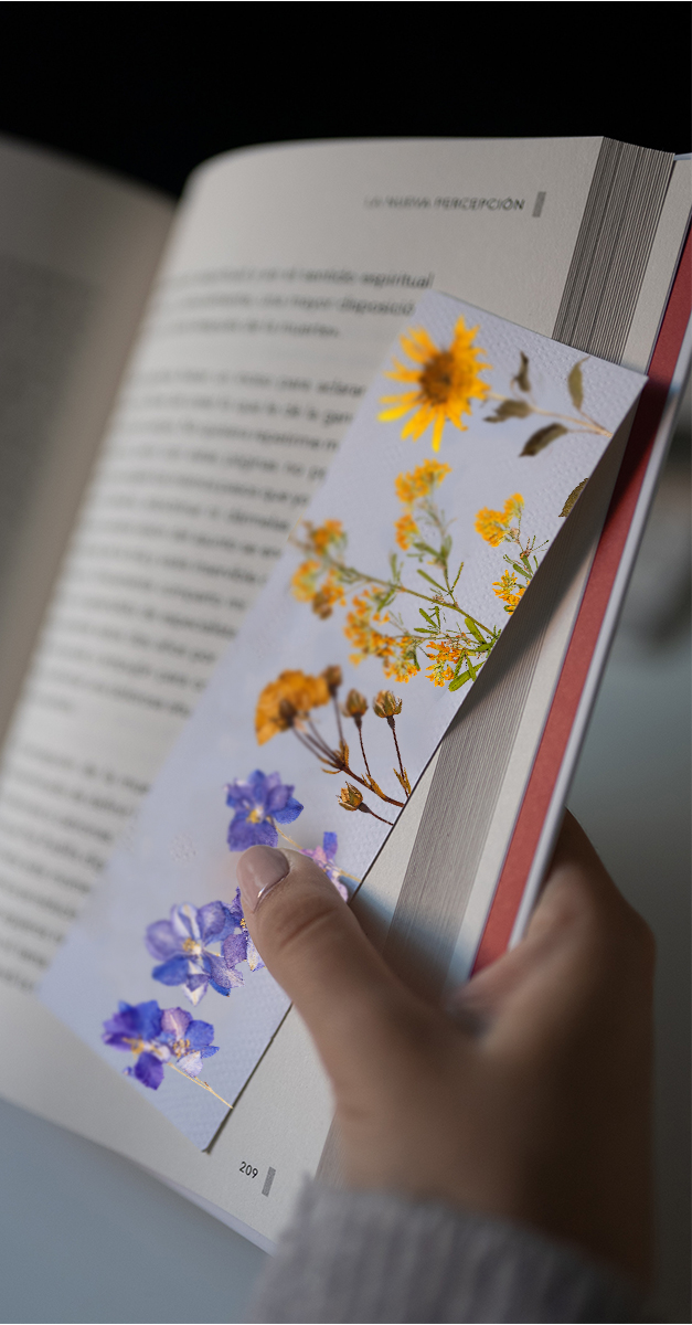 bookmark made with pressed flowers in a book held open by a hand