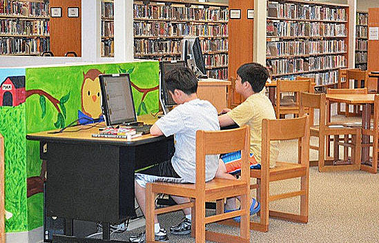 grade school boys on their computers at the library