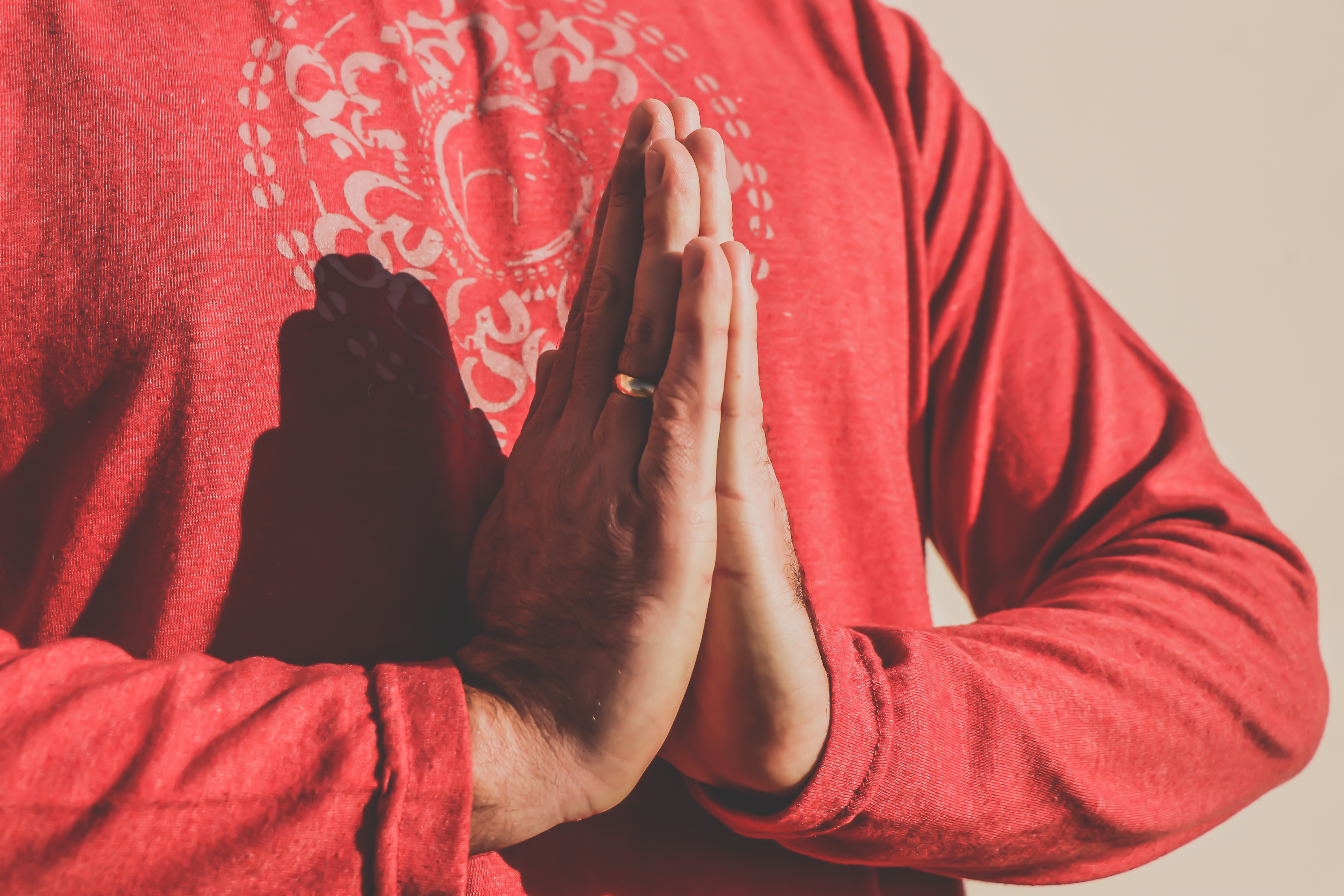 Person in red robe with hands in prayer