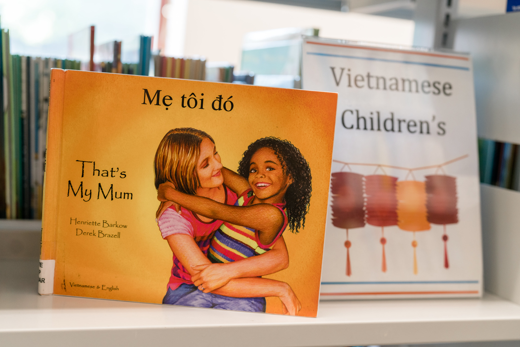 Library shelf displaying the children's picture book "That's My Mum" English and Vietnamese version next to a sign reading "Vietnamese Children's"