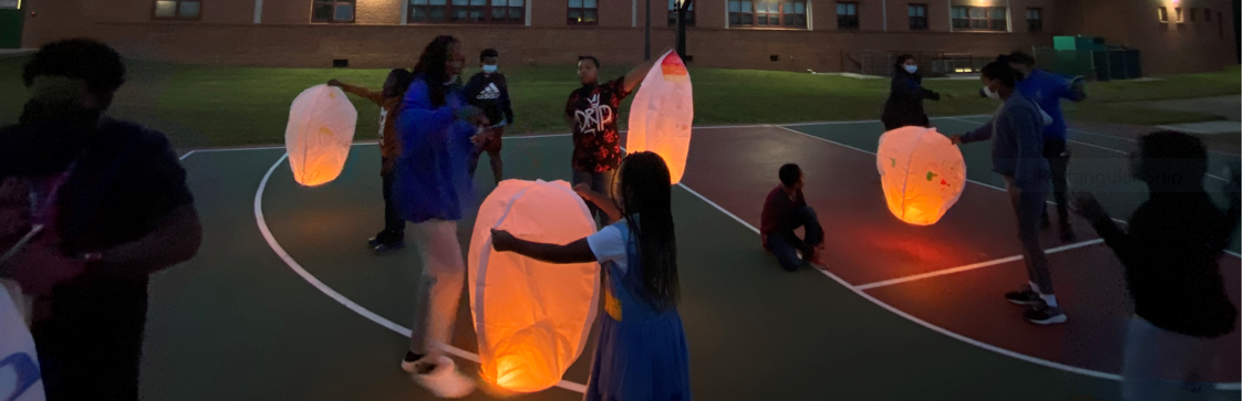 Students holding Chinese lanterns in the dark