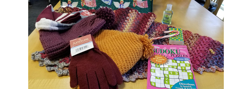 Photo of items included in a gift bag - blanket, hat, gloves, socks, candy and other items.