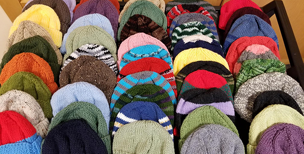 Photo of a tabletop full of knit winter hat donations