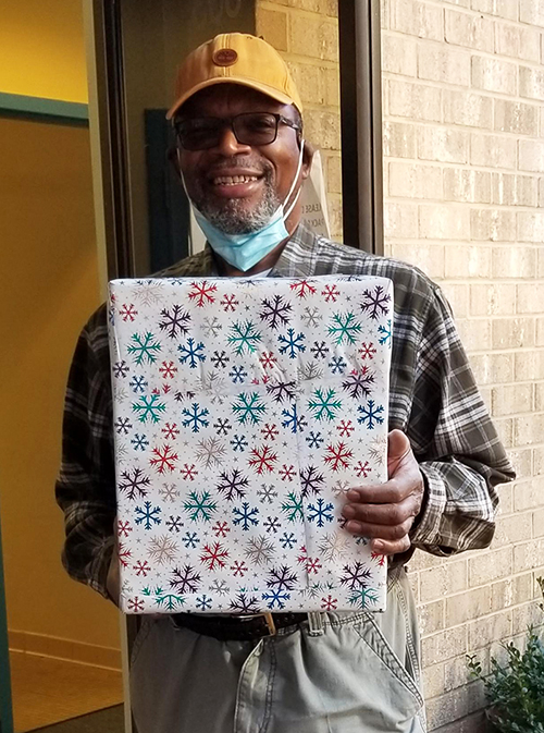 Homestretch employee holding a box of donated hats, scarves and gloves.