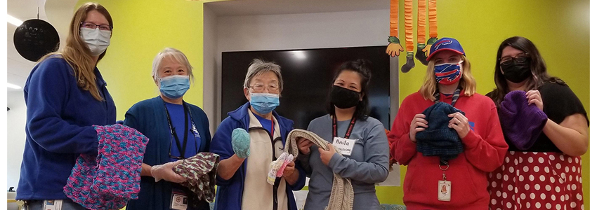 Group photo of six senior center staff holding items donated to the winter warming project.