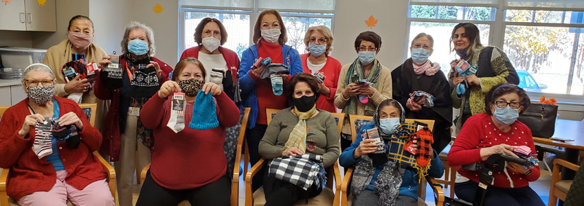 Group photo of the Pimmit Hills Iranian Elderly Foundation holding items donated to the winter warming drive.