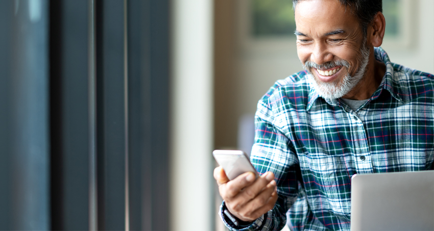 Man smiling while looking at smart phone