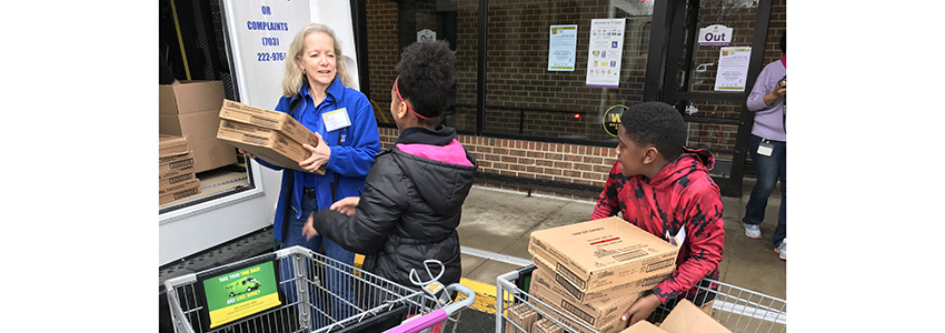 Volunteers load food donations into a Fastran bus.