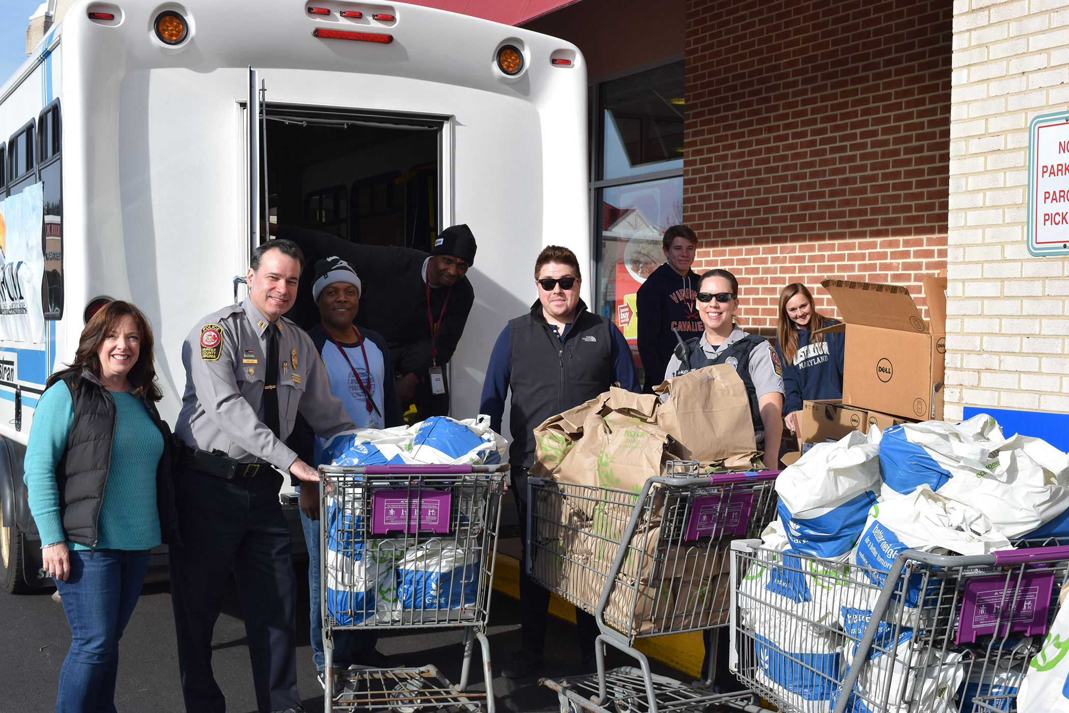 Volunteers pose with a Fastran bus filled with donated food.