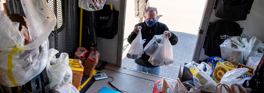 Photo of a man putting his bag of donated food on the Fastran bus parked at the Braddock District Supervisor’s Office.