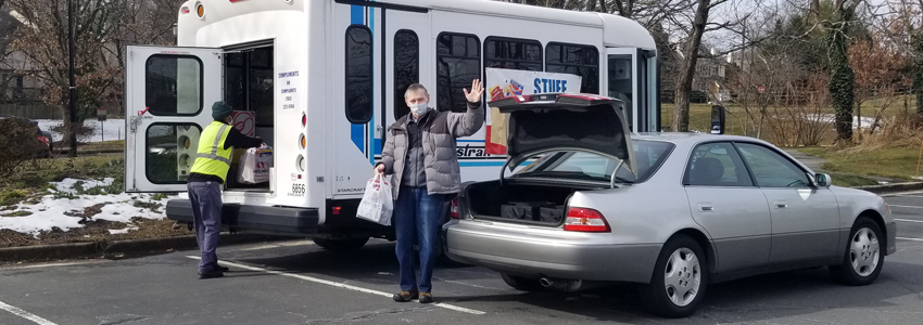 Photo of a man donating food to the Stuff the Bus food drive at Pohick Regional Library. 
