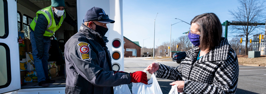 Photo of Sully District Supervisor Kathy Smith hands bags of food to a FCPD officer at the Sully Government Center.