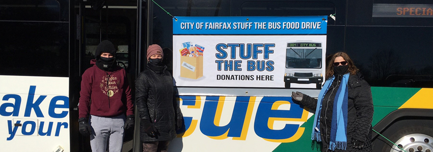 Photo of three volunteers in front of a Cue bus at Van Dyck park.