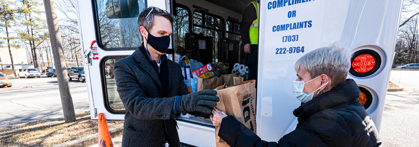 Photo of Braddock Supervisor Walkinshaw helping load donation onto a Fastran bus.