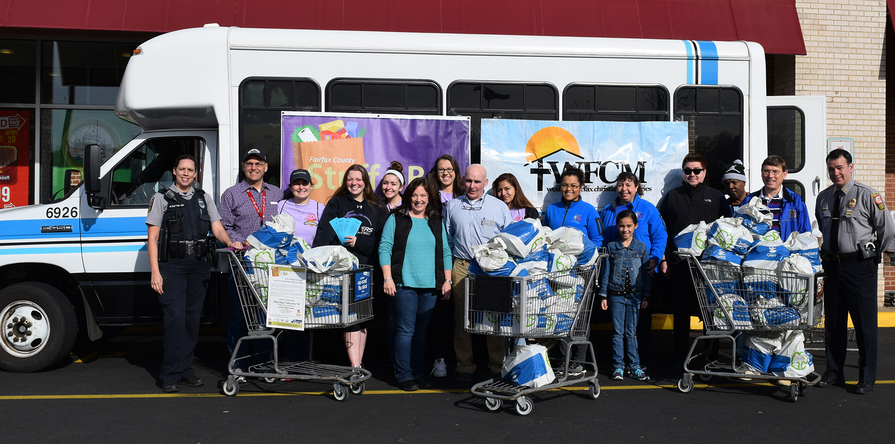 Volunteers post in front of a Fastran bus filled with donated food.