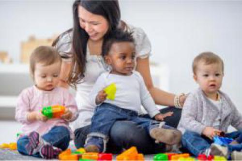 Image of child care provider and several children playing.