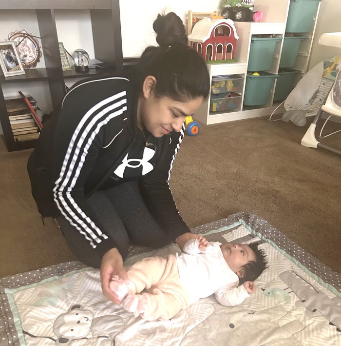 Woman playing with newborn baby on floor