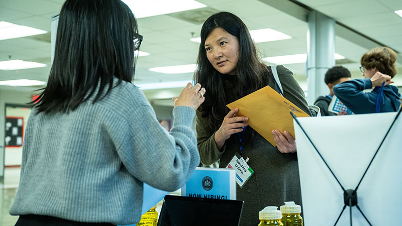 Two women talking alongside a table at an expo.
