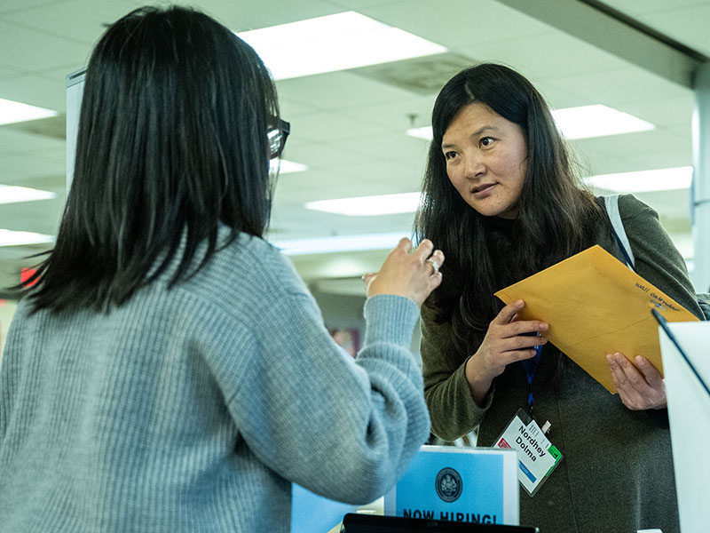 Two women talking alongside a table at an expo.