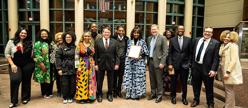 A group of adults smiling and posing with a framed certificate.