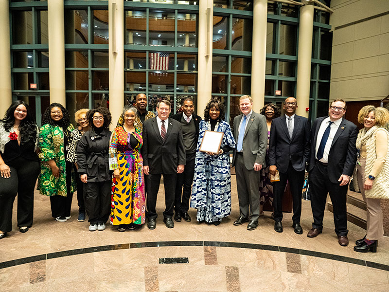 A group of adults smiling and posing with a framed certificate.