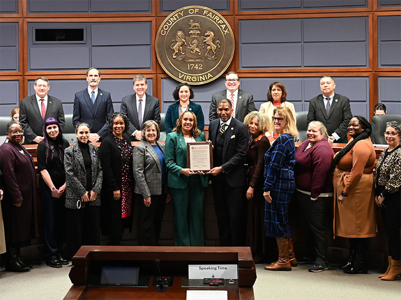 A group of adults smiling and posing with a framed certificate.