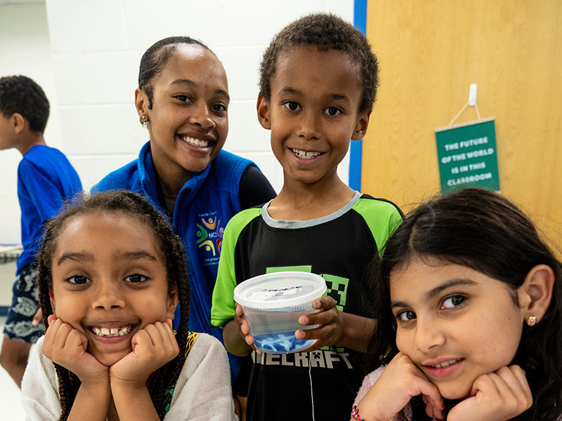 An NCS teacher with several youth smiling together.