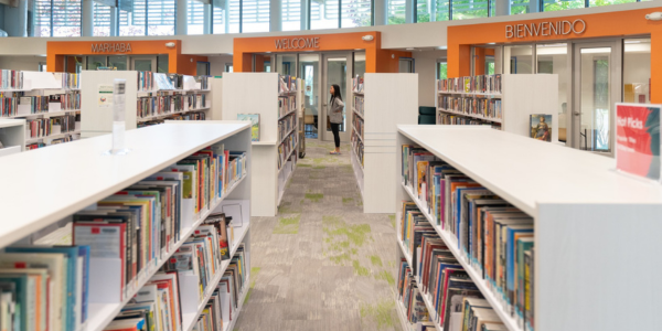 Image of an aisle in the library. Shelves are lines with children's books