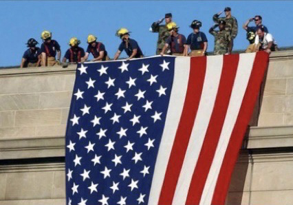 First responders hold an American Flag over the side of the Pentagon.