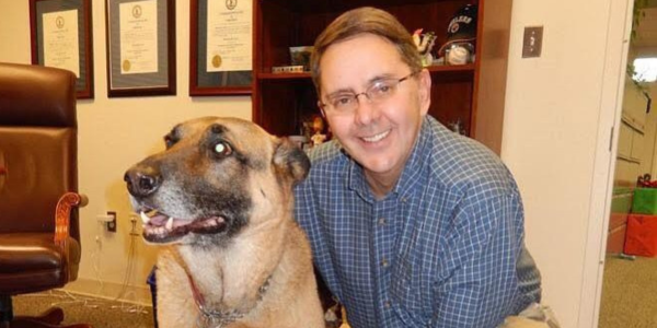 Former Sully District Supervisor Michael R. Frey smiles next to a German Shepherd. 