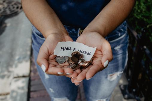 2022 Needs Assessment - Economic Factors Hands holding change and paper with "Make a Change" written on it.