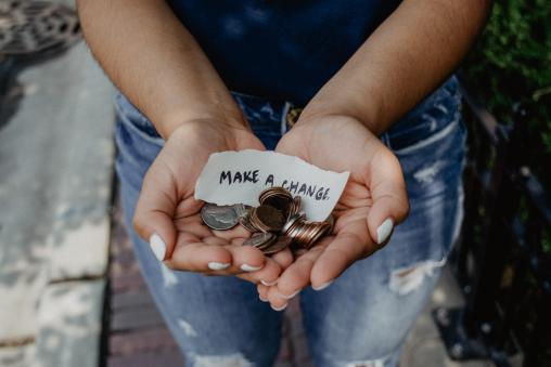 Hands holding change and paper with "Make a Change" written on it.