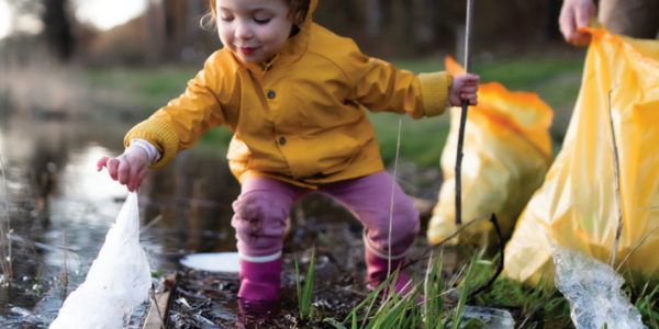 girl picking plastic bag out of water