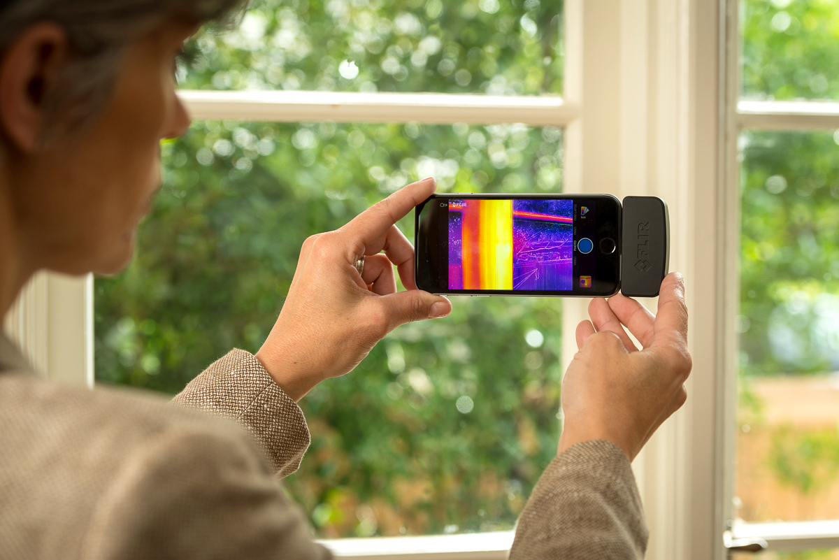 person holding thermal camera attached to cell phone