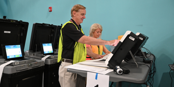 Image of election officers operating a ballot scanner. 
