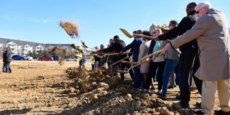 Line of people shovel dirt into the air to celebrate the start of construction for the Franconia Governmental Center and Kingstowne Regional Library.